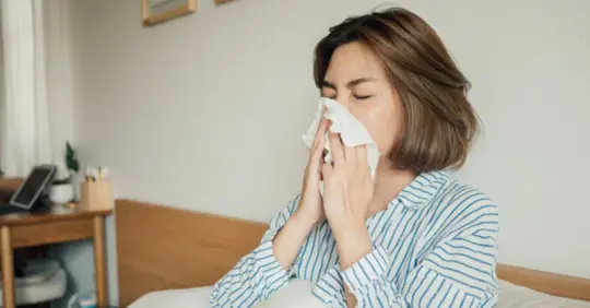 woman blowing her nose in bed