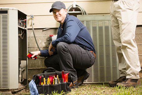 an air conditioning technician performing maintenance or repair on an outdoor air conditioning unit