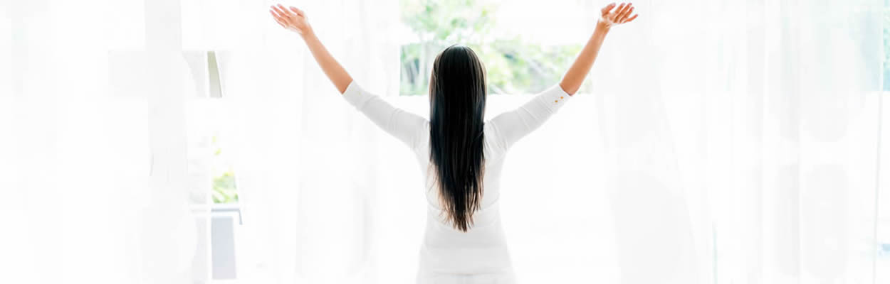 Woman Standing At Window Enjoying Sunshine