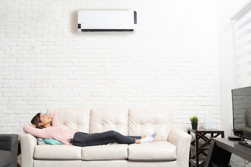 Woman relaxing on couch under ductless unit