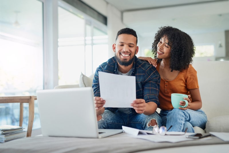 happy Couple Paying Bills on couch