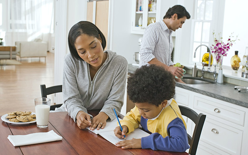 parent helping child with homework at table